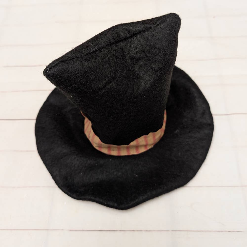 Black hat with plaid band on a light wooden surface
